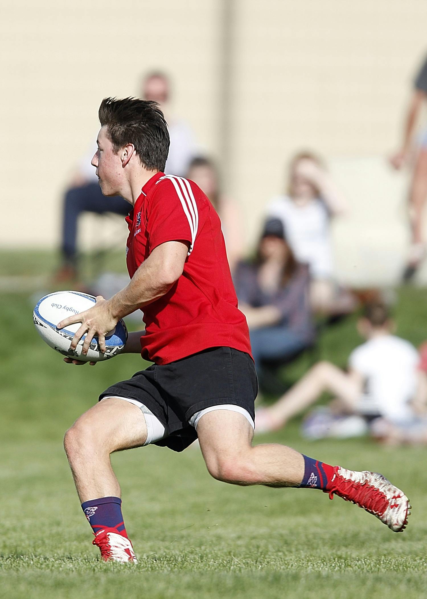 Rugby player in action, sprinting across a sunny field, showcasing athleticism.